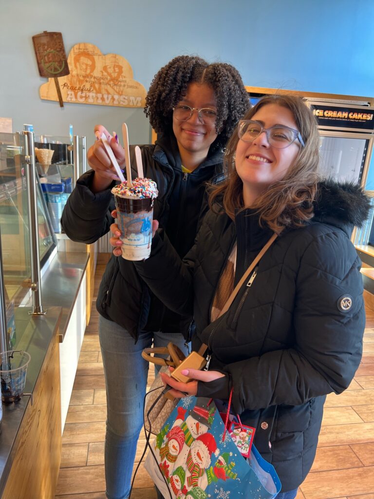Two women hold a four-scoop ice cream sundae at a Ben & Jerry's.