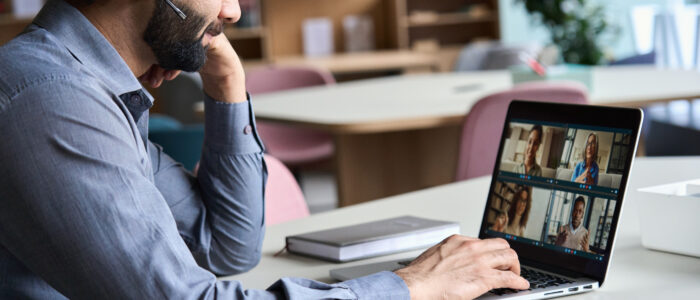 Indian business man wearing headset having virtual team meeting on video conference call using laptop work from home office talking to diverse people group in remote teamwork online distance chat.